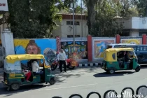 Tuk Tuks passing street art on walls in a Lucknow street.